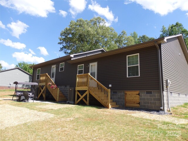 back of property with stairway, a lawn, and crawl space