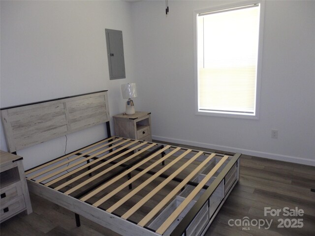 unfurnished bedroom featuring electric panel, wood finished floors, and baseboards