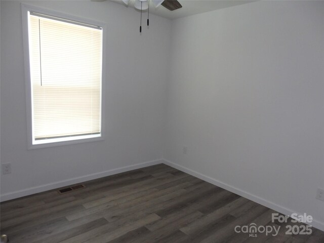 spare room featuring dark wood finished floors, a ceiling fan, and baseboards