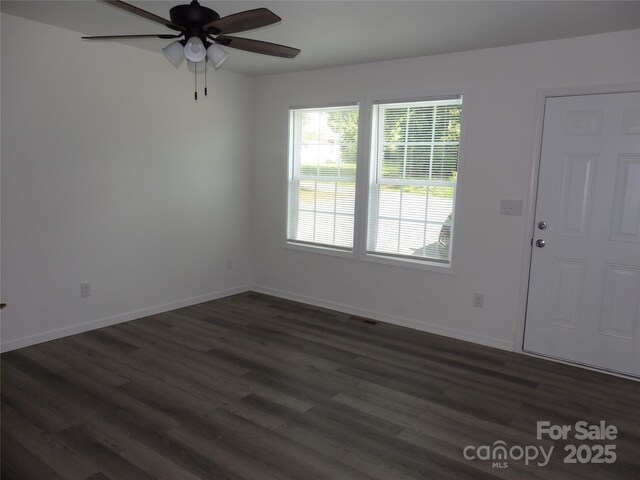 spare room with a ceiling fan, dark wood-style floors, and baseboards