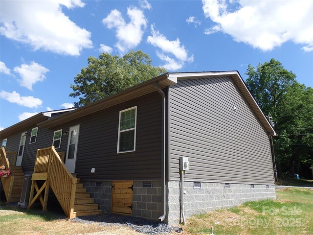 view of side of property featuring crawl space and stairway