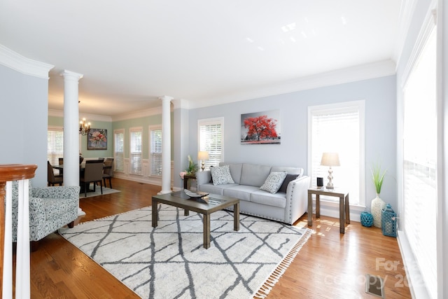living room featuring ornamental molding, visible vents, decorative columns, a chandelier, and light wood-style floors