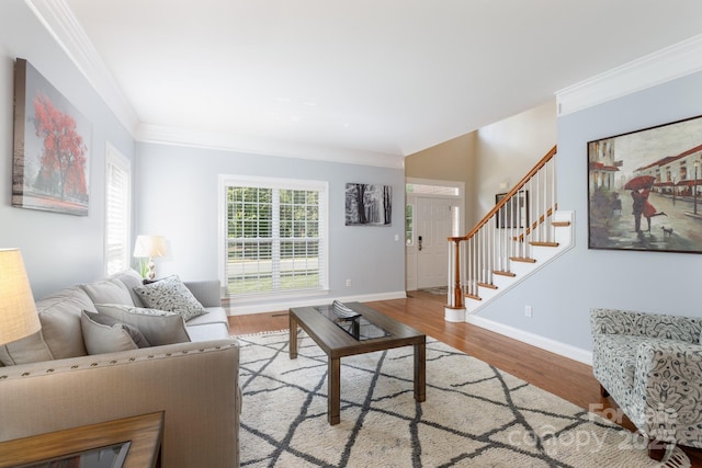 living area with baseboards, stairs, ornamental molding, and wood finished floors