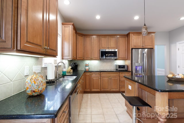 kitchen featuring a sink, brown cabinets, backsplash, light tile patterned floors, and appliances with stainless steel finishes