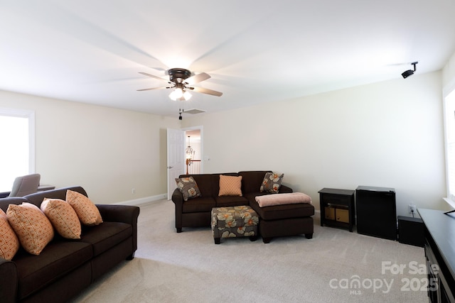 living room with light carpet, baseboards, and a ceiling fan