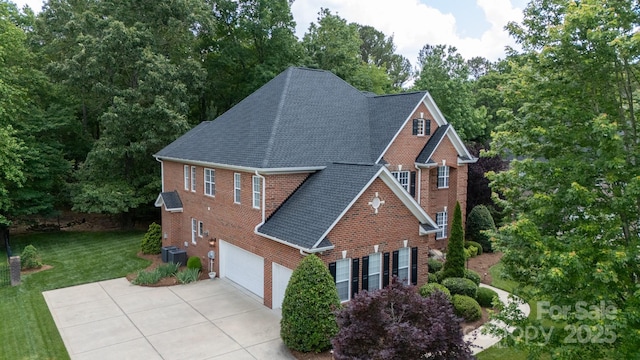 view of side of home with brick siding, roof with shingles, and a garage