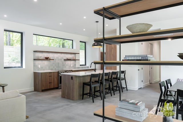 129 English Dr, Candler, NC 28715 - kitchen with high end stainless steel range oven, light countertops, tasteful backsplash, concrete floors, and a breakfast bar area