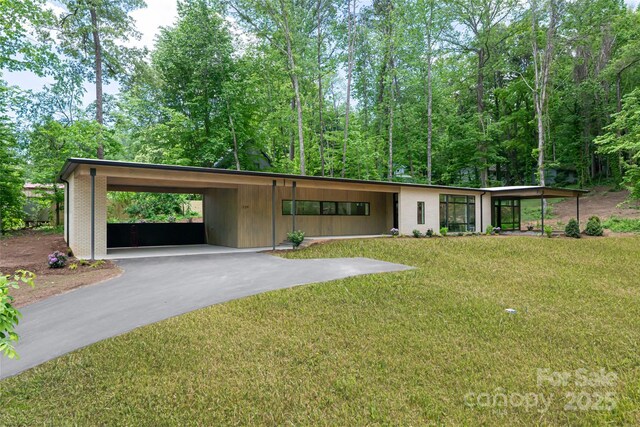 129 English Dr, Candler, NC 28715 - mid-century home featuring a front yard, driveway, a carport, and brick siding