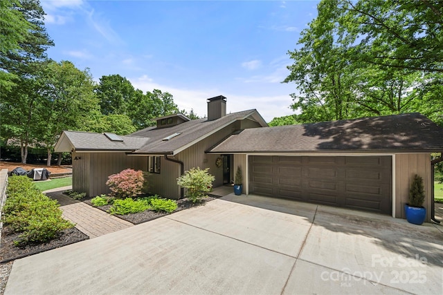 mid-century inspired home featuring driveway, a chimney, an attached garage, and roof with shingles