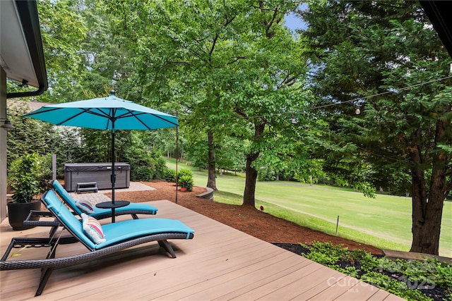 wooden terrace with a hot tub, a lawn, and view of wooded area