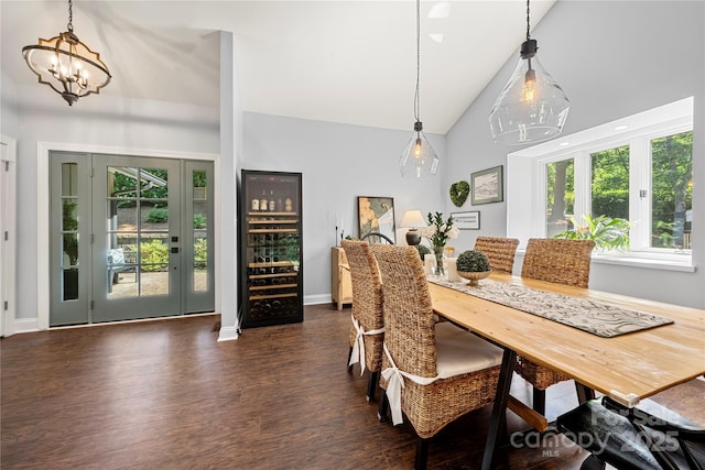 dining space with dark wood-type flooring, a chandelier, baseboards, and high vaulted ceiling