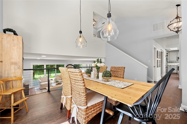 dining space featuring high vaulted ceiling, dark wood finished floors, a chandelier, and stairway
