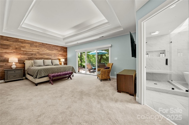 bedroom featuring a raised ceiling, access to exterior, light carpet, wooden walls, and ensuite bathroom