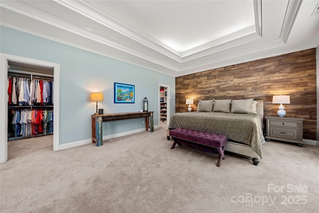 bedroom with a spacious closet, a closet, carpet flooring, and wooden walls