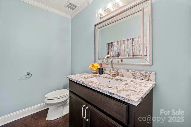 half bath featuring ornamental molding, wood finished floors, baseboards, toilet, and vanity
