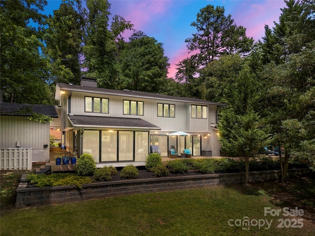 rear view of house featuring a sunroom, a yard, and a chimney