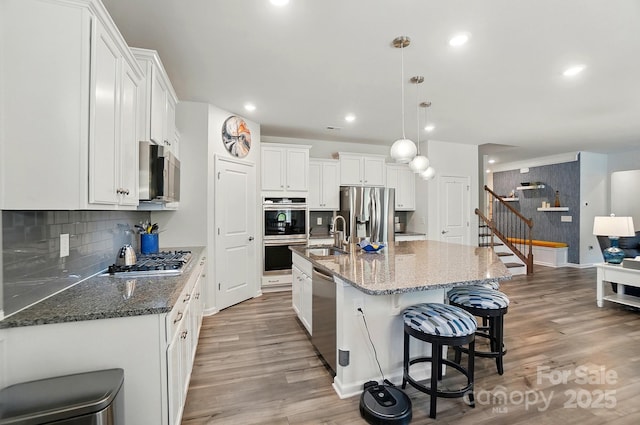 1360 Dali Blvd, Mount Holly, NC 28120 - kitchen featuring stainless steel appliances, wood finished floors, white cabinetry, a kitchen bar, and a sink