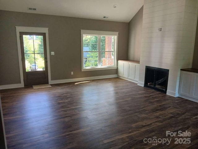 unfurnished living room with baseboards, dark wood finished floors, visible vents, and a large fireplace