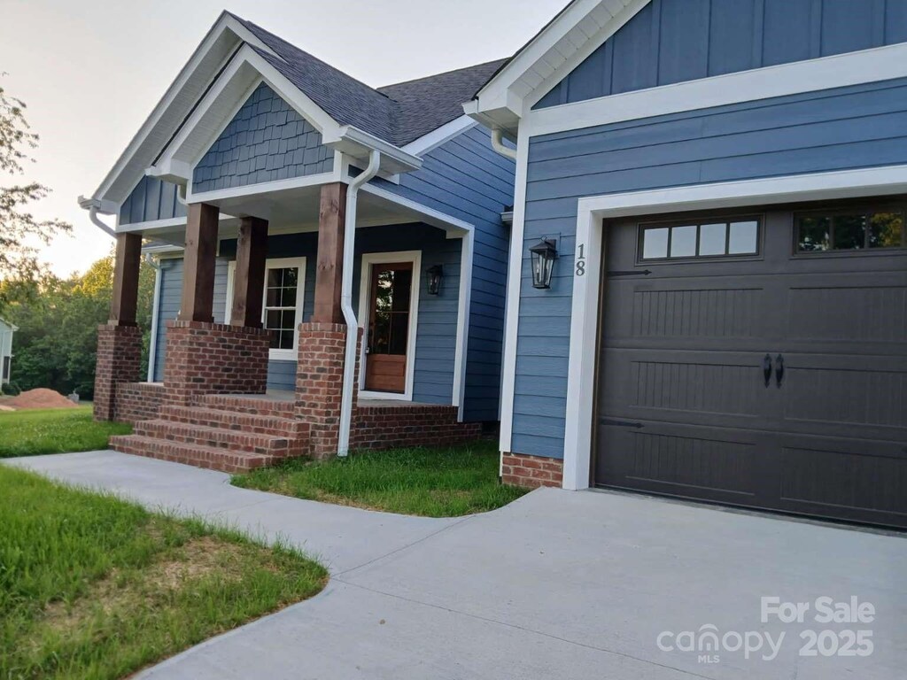 18 Morningside Dr, Granite Falls, NC 28630 - property entrance featuring covered porch, a garage, driveway, and board and batten siding