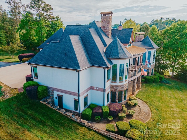 back of house with a chimney, a lawn, stone siding, and stucco siding