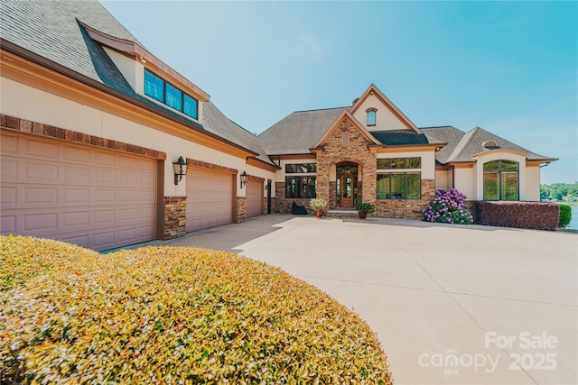 craftsman-style house featuring stone siding, concrete driveway, an attached garage, stucco siding, and roof with shingles