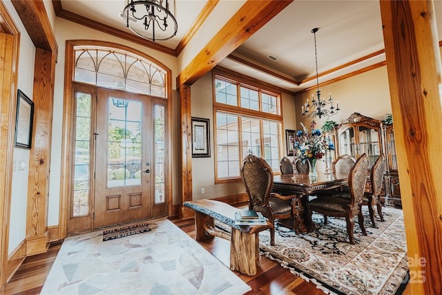 foyer featuring a chandelier, ornamental molding, wood finished floors, and baseboards