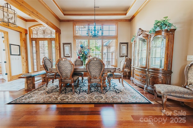 dining space featuring a chandelier, plenty of natural light, a raised ceiling, crown molding, and hardwood / wood-style floors