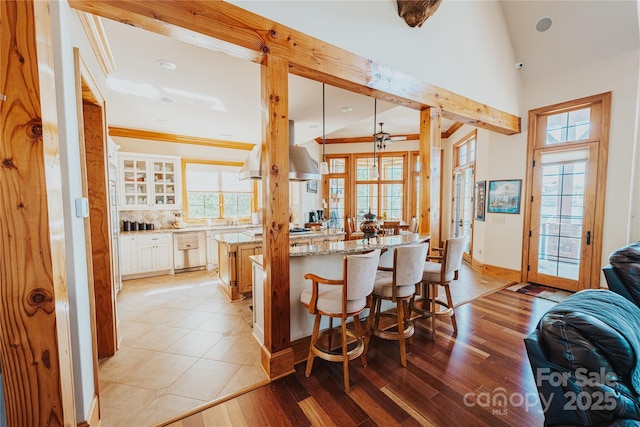kitchen featuring open floor plan, a breakfast bar area, backsplash, light wood-type flooring, and light stone counters