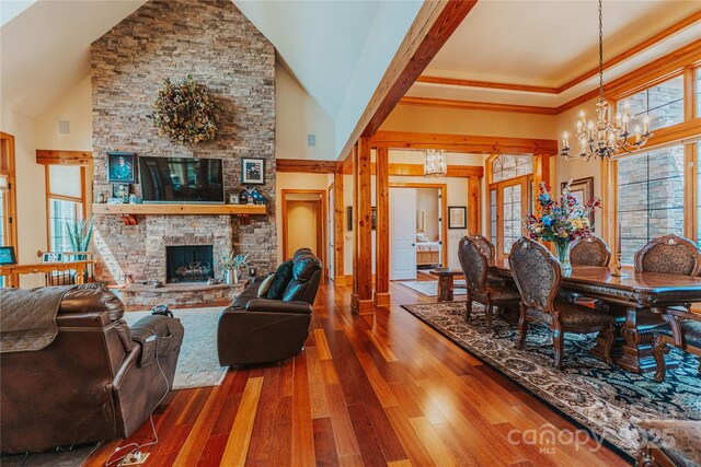 living room with a chandelier, high vaulted ceiling, dark wood finished floors, and a fireplace