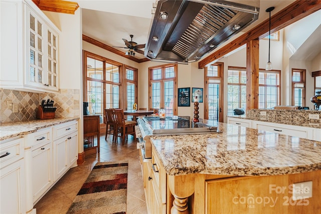 kitchen featuring a ceiling fan, exhaust hood, backsplash, glass insert cabinets, and light tile patterned flooring