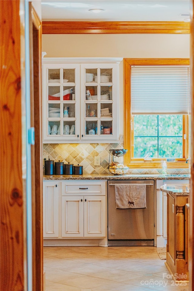 kitchen with stainless steel dishwasher, tasteful backsplash, glass insert cabinets, white cabinets, and ornamental molding
