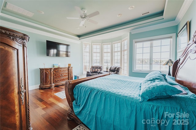 bedroom with a tray ceiling, multiple windows, wood finished floors, ornamental molding, and recessed lighting