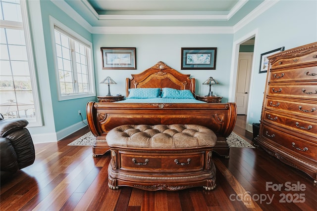 bedroom featuring hardwood / wood-style flooring, crown molding, baseboards, and a tray ceiling
