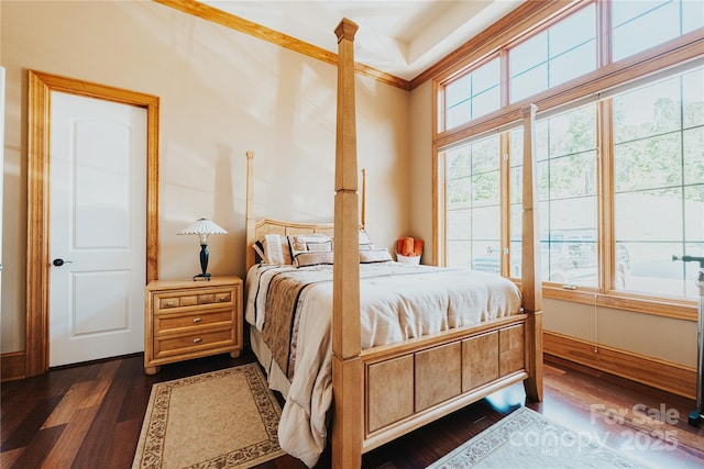 bedroom featuring dark wood-type flooring, ornamental molding, and baseboards