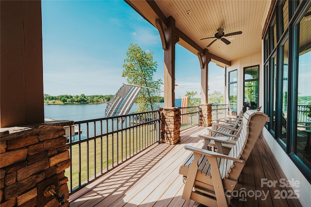 deck with a water view and ceiling fan