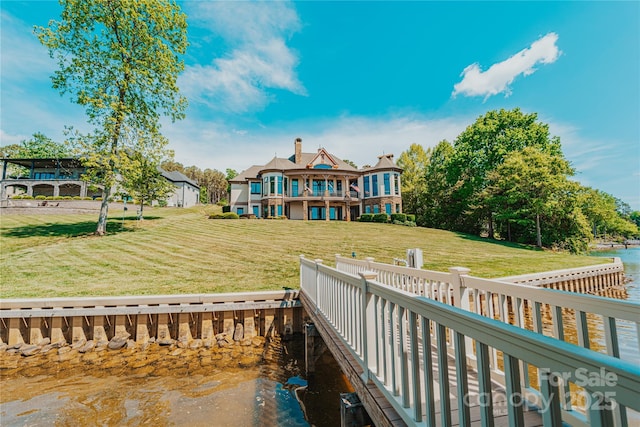 back of house featuring a water view, a yard, and a chimney