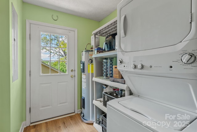 11 Louisville Pl, Asheville, NC 28806 - laundry area with stacked washer / drying machine, electric water heater, light wood-type flooring, a textured ceiling, and baseboards