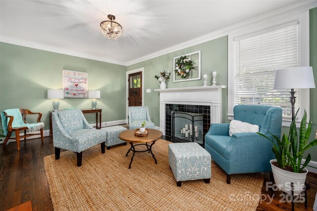 living room with a fireplace, crown molding, wood finished floors, baseboards, and a chandelier