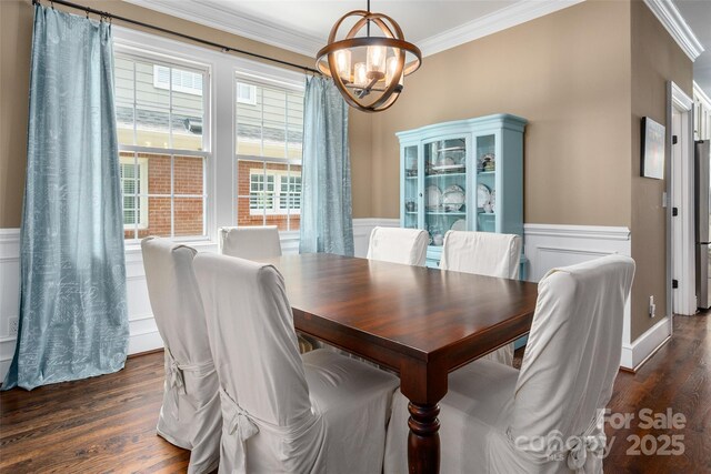 dining room featuring a chandelier, crown molding, wainscoting, and dark wood finished floors