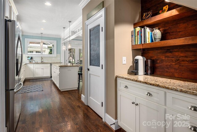 kitchen featuring stainless steel refrigerator with ice dispenser, dark wood-type flooring, light stone counters, backsplash, and crown molding