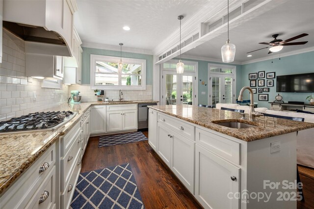 kitchen with a sink, french doors, appliances with stainless steel finishes, a center island with sink, and crown molding