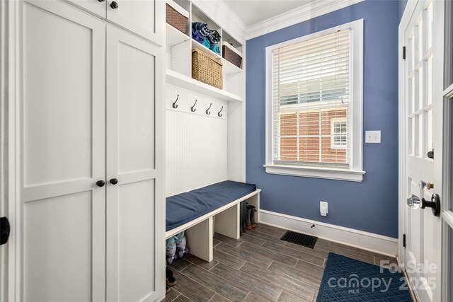 mudroom with baseboards, crown molding, and wood tiled floors