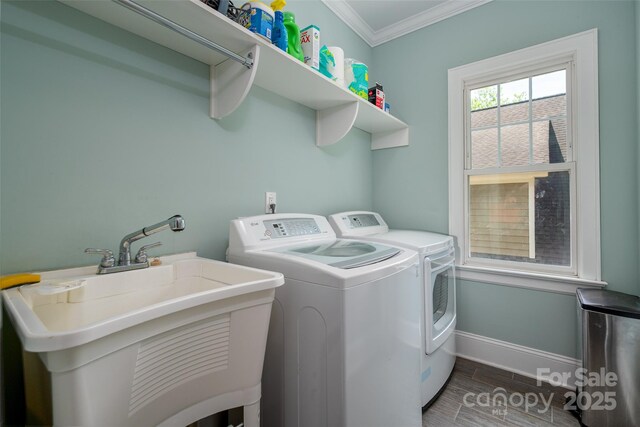 clothes washing area with crown molding, separate washer and dryer, baseboards, and wood finished floors