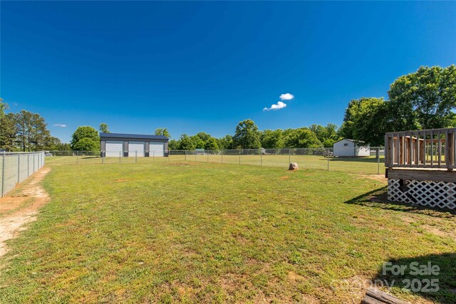 view of yard featuring a storage unit, an outbuilding, a garage, and a wooden deck