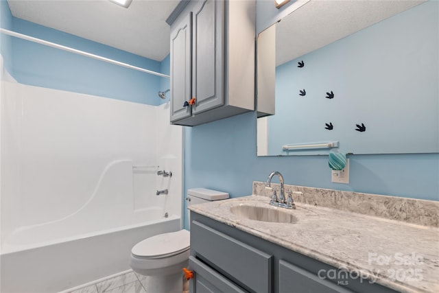 full bath featuring toilet, vanity, marble look tiles, and washtub / shower combination