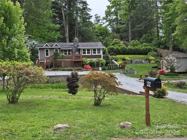 view of front facade with a deck, a front yard, a chimney, and driveway