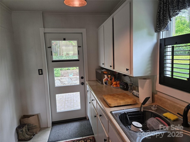 interior space with crown molding, tile patterned flooring, and a sink