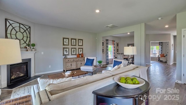 living area with wood finished floors, visible vents, recessed lighting, baseboards, and a glass covered fireplace