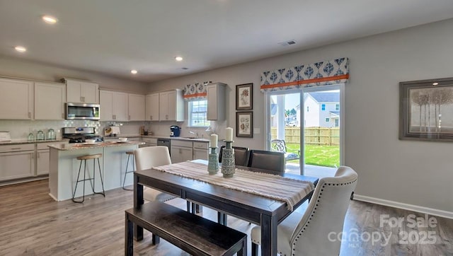 dining room with light wood-type flooring, visible vents, baseboards, and recessed lighting