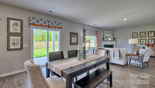 dining space with wood finished floors, visible vents, recessed lighting, a fireplace, and baseboards